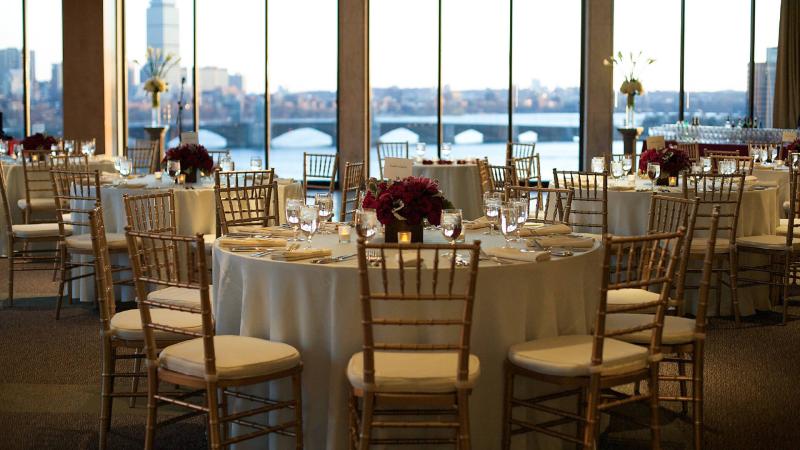 Tables and chairs set for a formal event in the Skyline room, overlooking the Charles river.