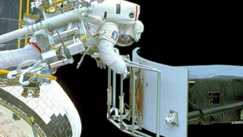 An astronaut floating in space, fixing the Hubble Space Telescope. 