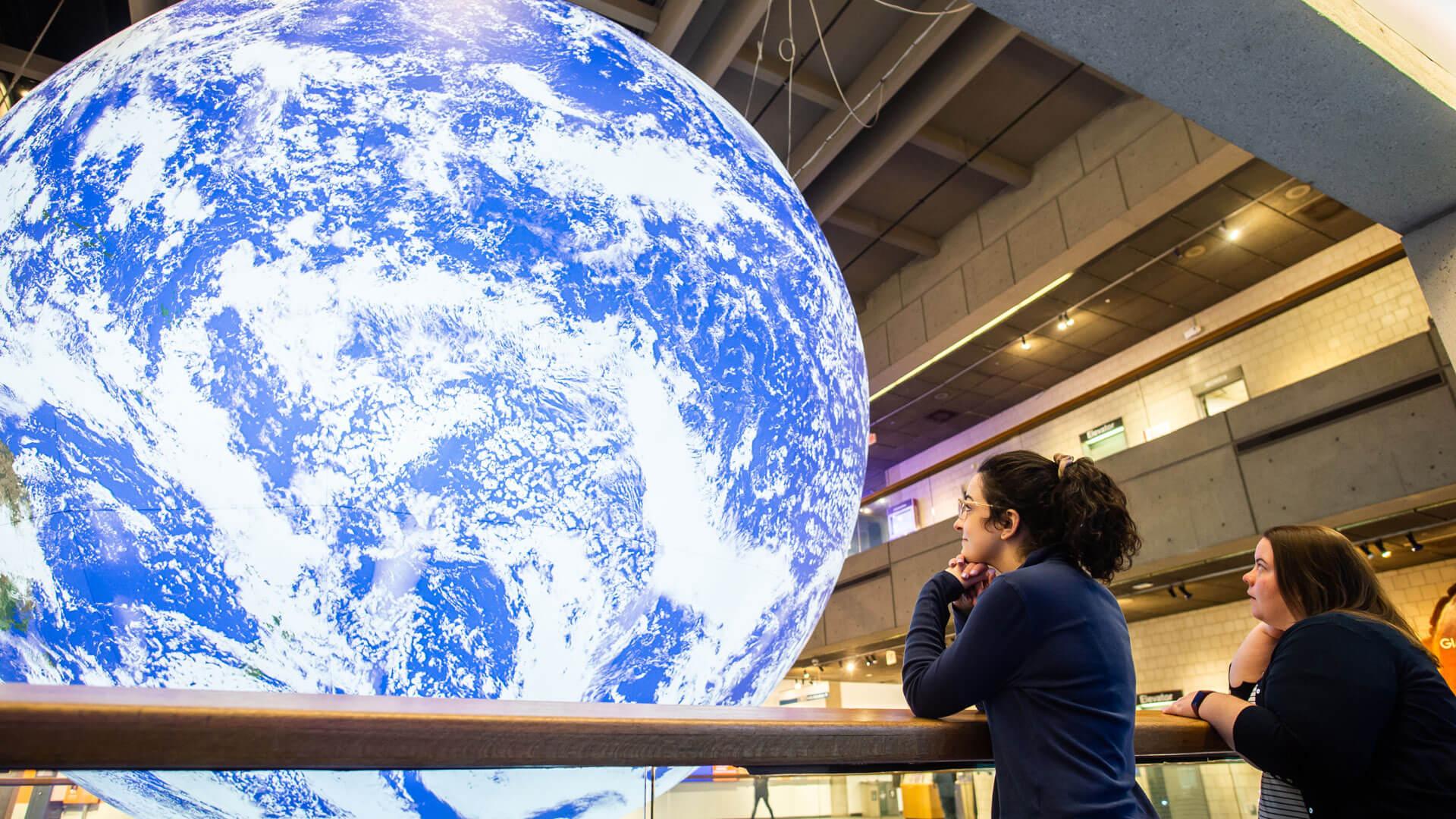 Two guests looking up at the Gaia globe.