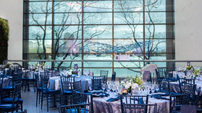 Tables and chairs set up in the Museum lobby, overlooking the Charles River.