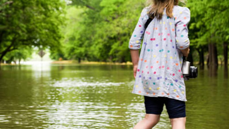 A young girl in rain boots by a lake.