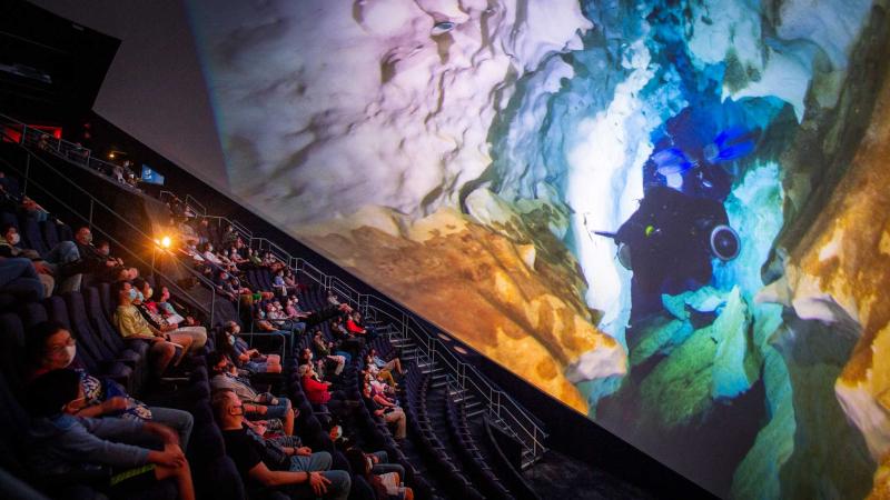 Visitors watching an omni movie about cave diving.
