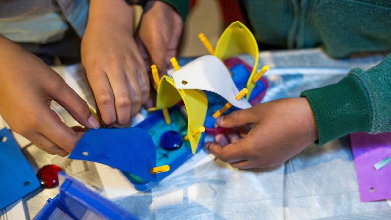 A close up of hands working on an engineering challenge.