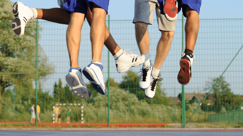 A group of people in sneakers and shorts jump on a basketball court