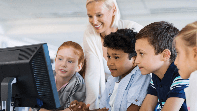A group of young students sit in front of a computer