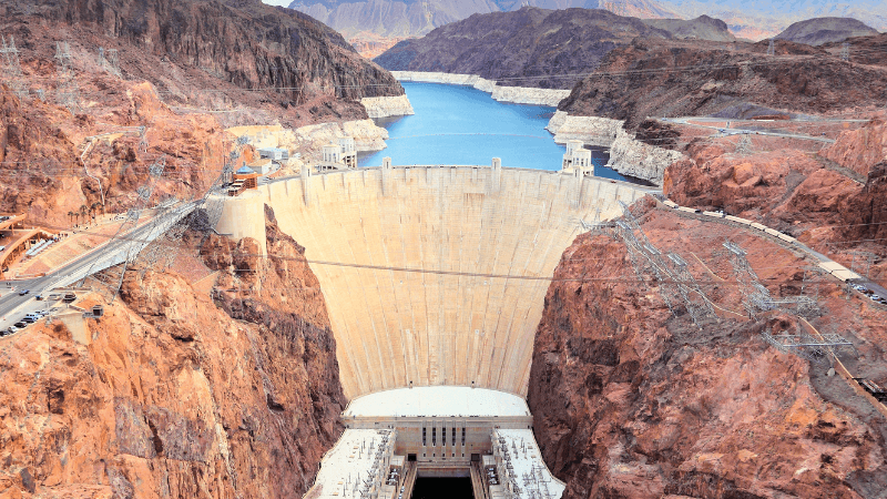 The Hoover Dam holds back water while surrounded by large red cliffs