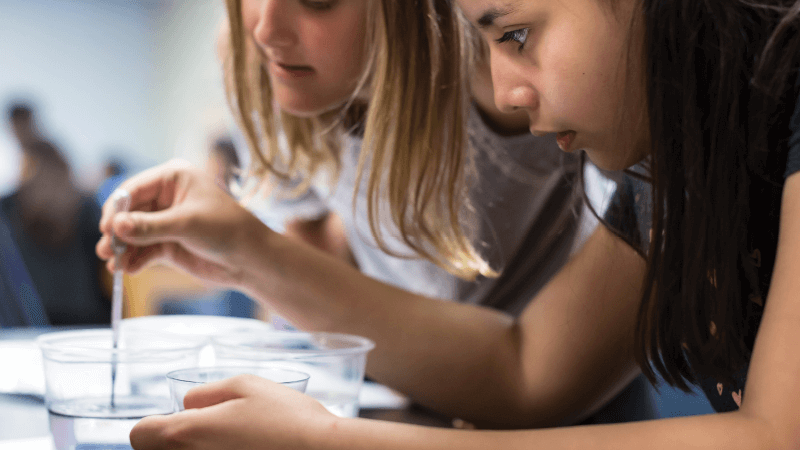 Two students do an experiment pipetting water
