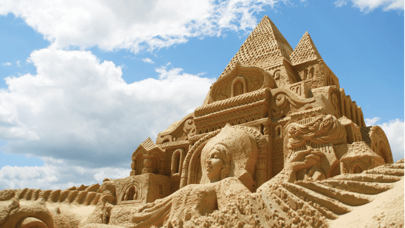 An ornate sand castle towers against the blue sky