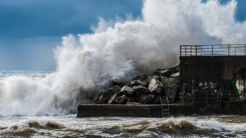 A large wave hits a levy next to the ocean