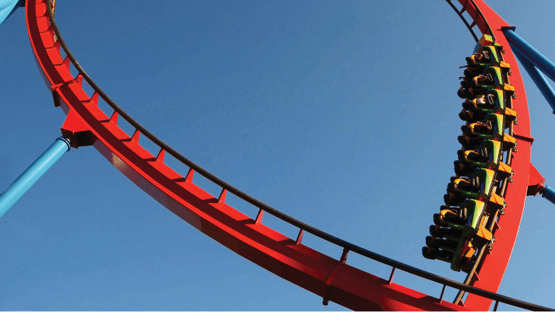 A roller coaster car starts to make a loop against the blue sky