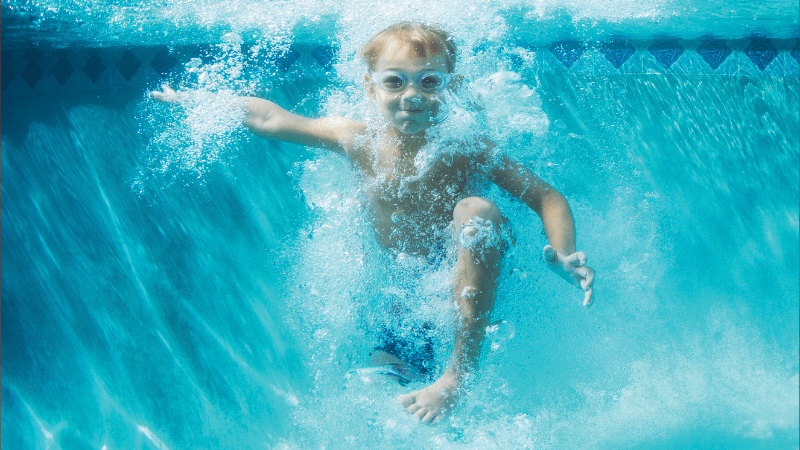 A child underwater after jumping into a pool