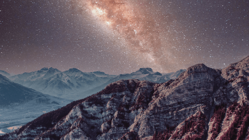 The Milky Way appears over rocky mountains