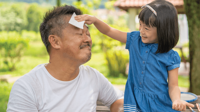 A child wipes sweat off an adults forehead while laughing