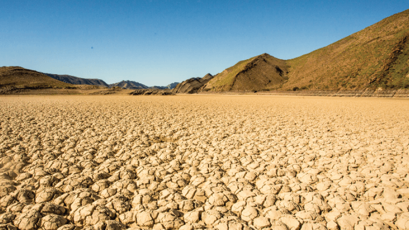 A dry desert with low mountains against a blue sky