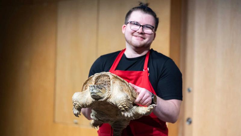 A museum eductaor holding a snapping turtle.