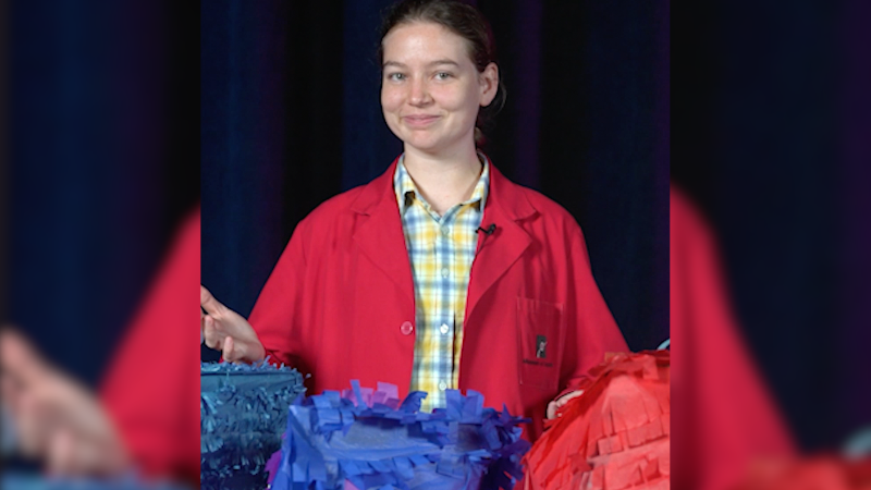 A museum educator with colorful piñatas on a black background