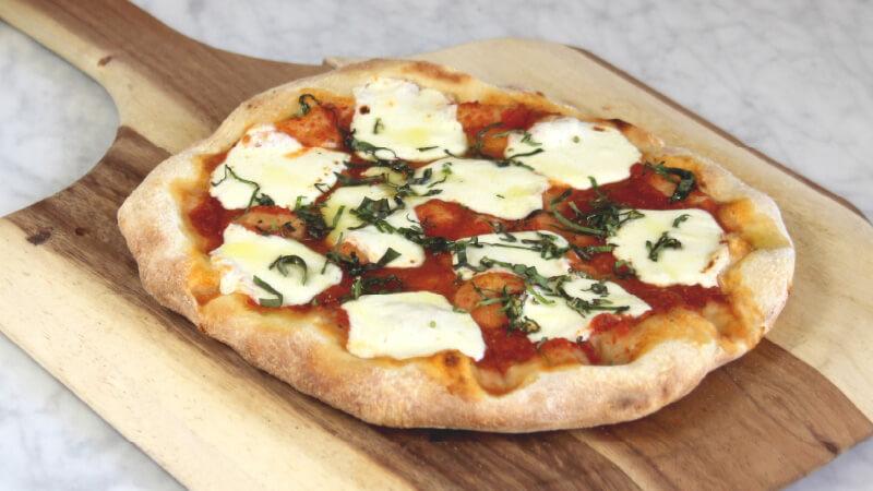 A flatbread pizza with tomato, mozzarella, and basil.