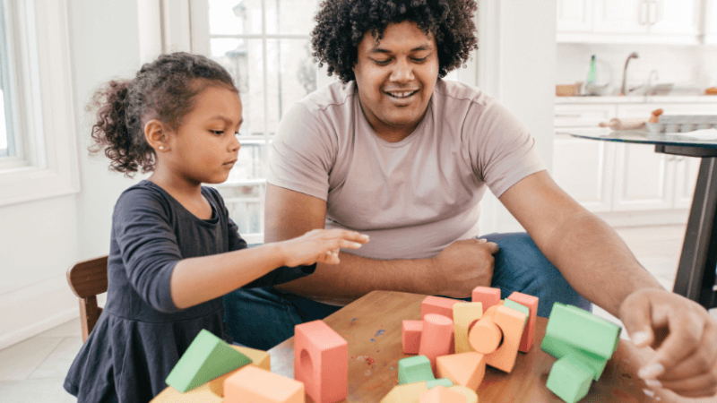 An adult and child stack colorful blocks