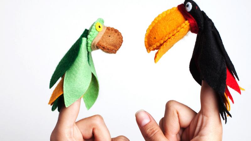 Image of two finger puppets: a black parrot and a green parrot.