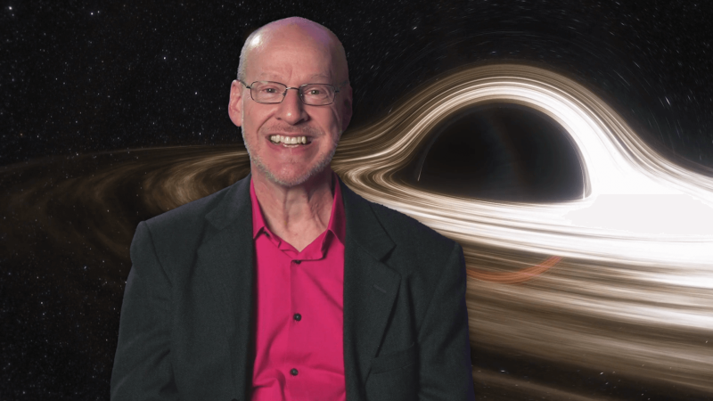 Phil Plait in front of an image of a black hole