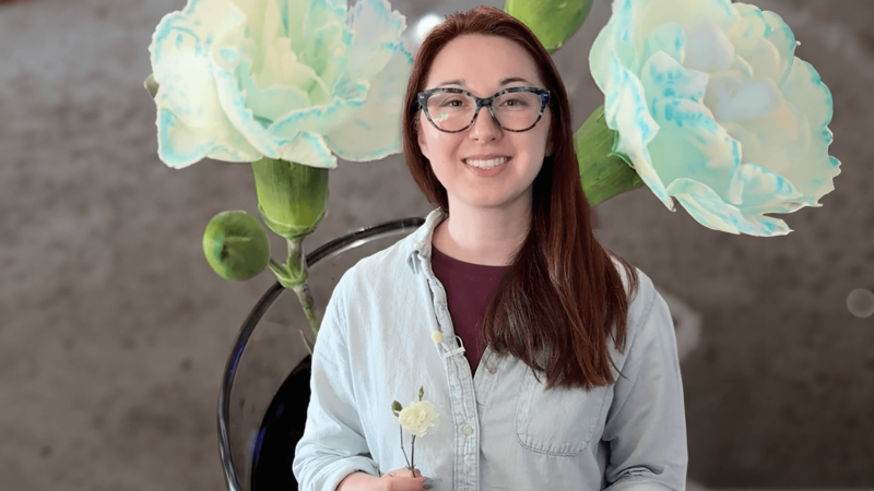 Alex Dainis in front of an image of roses that are colored blue
