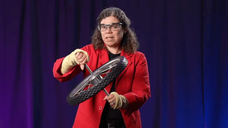 Museum Educator Jeannine holding a bike wheel