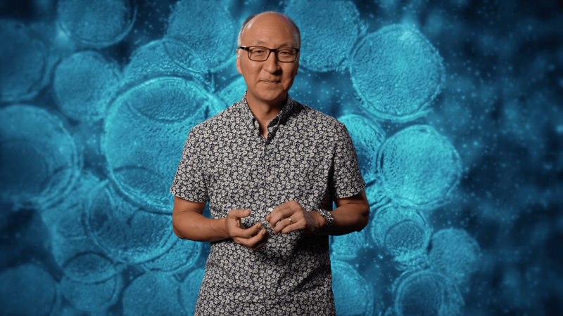 Insoo Hyun in front of an image of teal cells