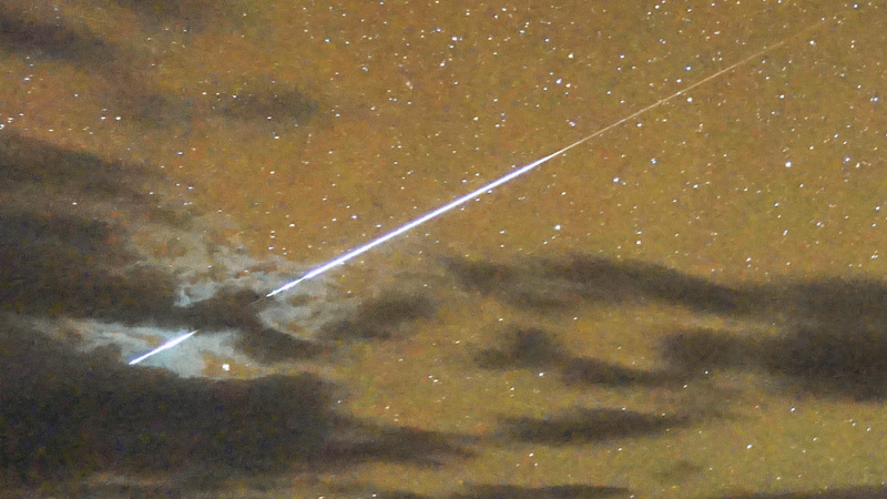 A bright meteor in an orange night sky