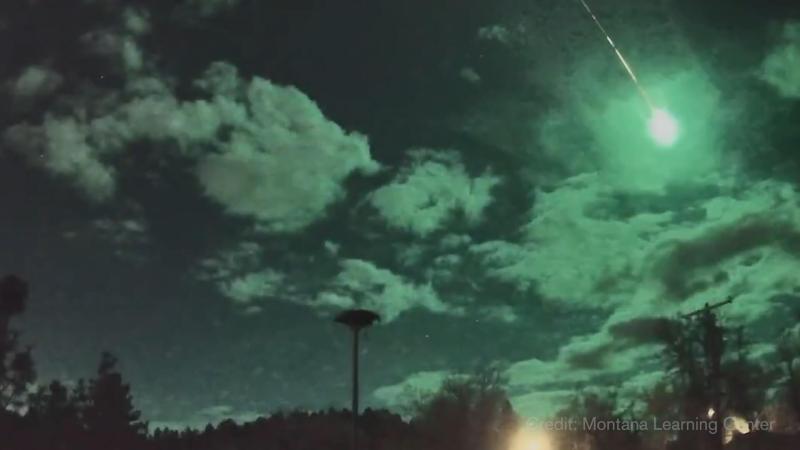 A picture of a green fireball shooting through the night sky