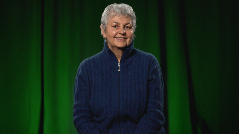 Yve Torrie in front of a black curtain with green lights