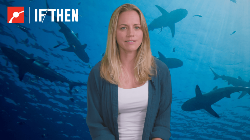 Jess Cramp in front of an underwater view of sharks
