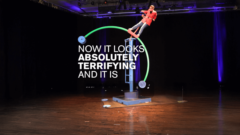 An educator standing on top of a half circle structure tilting with white text reading "Now it looks absolutely terrifying and it is"
