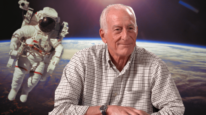 Dr. Jeff Hoffman in front of an image of him on a spacewalk in front of Earth