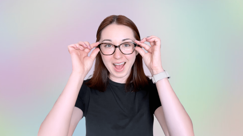 Alex Dainis in front of a pink, yellow, and green ombre background holding onto either side of her glasses.