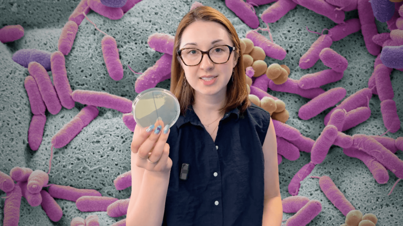 Alex Dainis in front of a microscopic view of bacteria