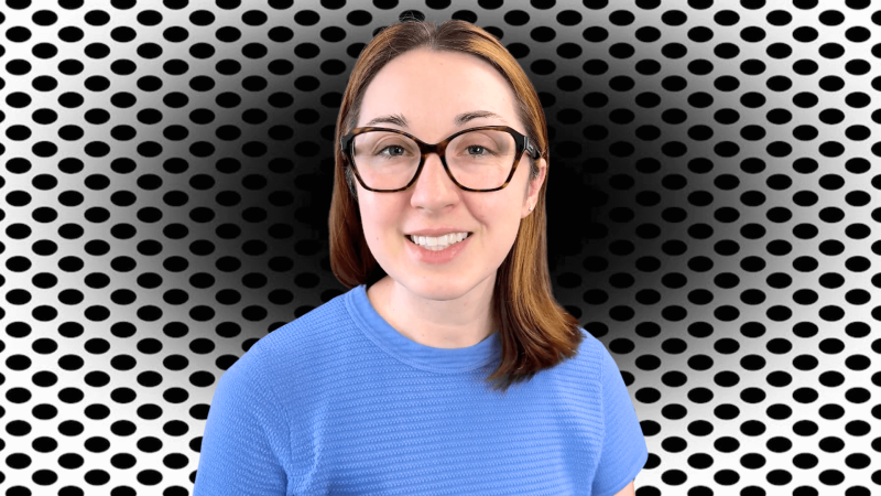 Alex Dainis in front of a white background with black dots.