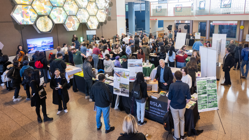 A career fair filled with young professionals networking, engaging in discussions, and exploring job opportunities at various company booths.