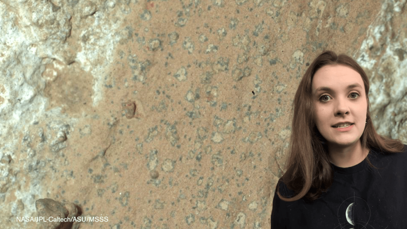 Educator Eva in front of an image of leopard rock on Mars