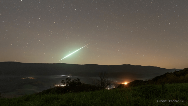 A taurid meteor glows green in a foggy sky.