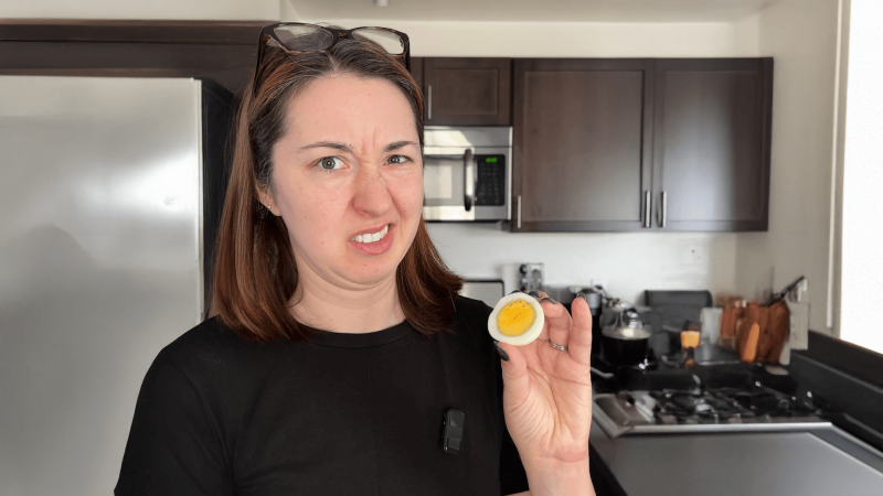 Alex Dainis making a face while holding a hardboiled egg.