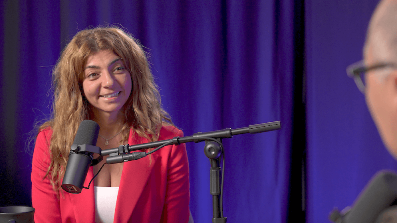 Rana Elkaliouby smiles in front of a purple lit curtain.