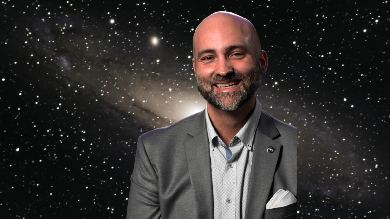 Paul Sutter in front of an image of a galaxy