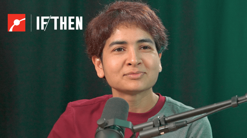Deblina Sarkar in front of a black curtain lit in green light.