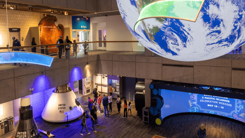 A view of the Museum of Science Blue Wing Lower Level showing Lunar Lander models and a large model Earth.