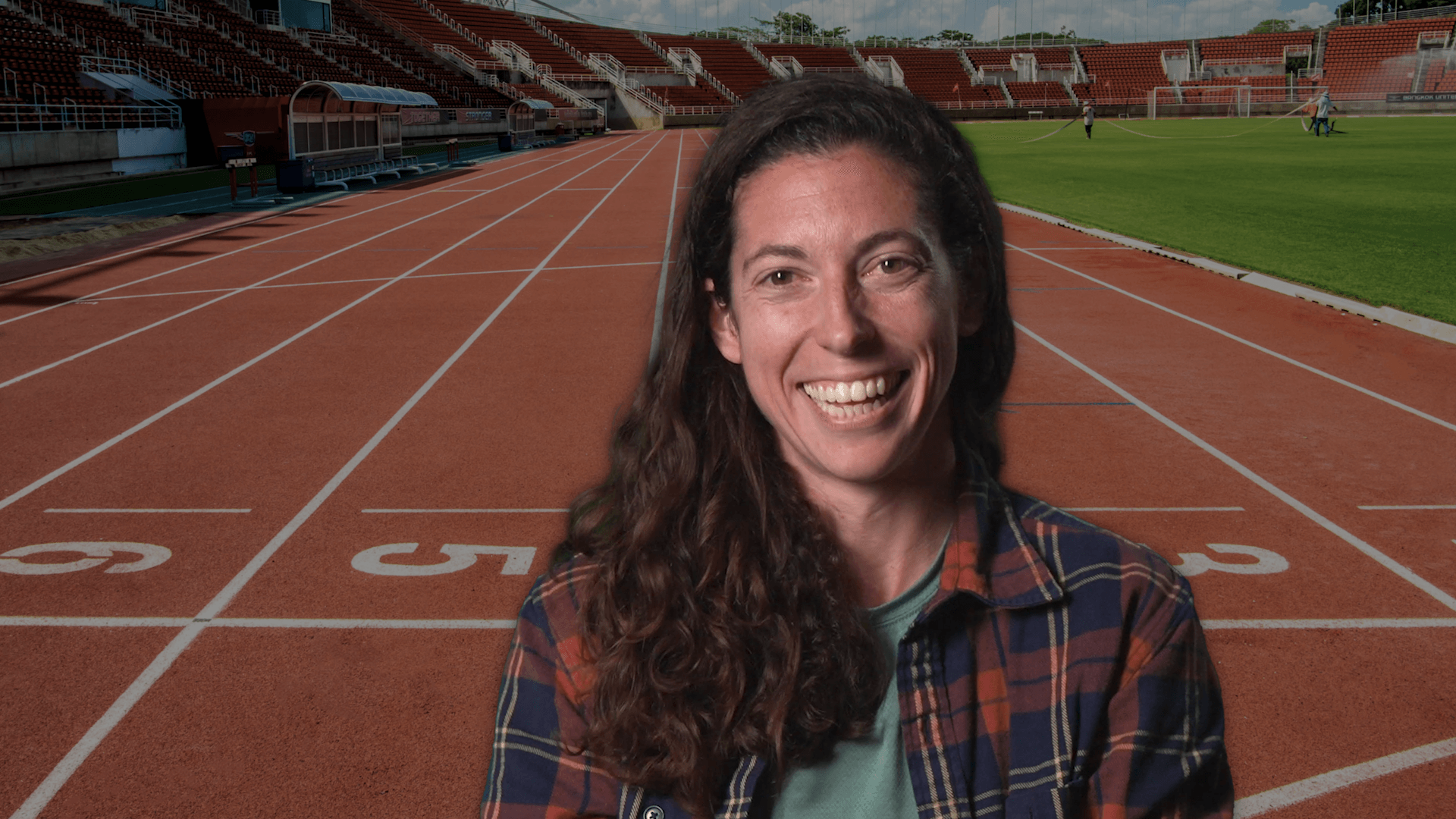 Lauren Kuntz smiling with a track behind her.