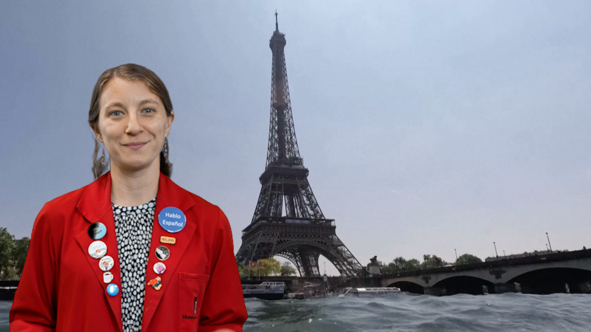 Museum Educator Sloane in a red lab coat with Seine River and Eiffel Tower behind her. 