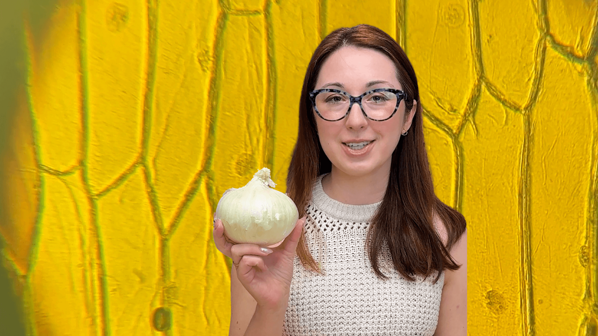 Alex Dainis standing in front of an onion while holding an onion.