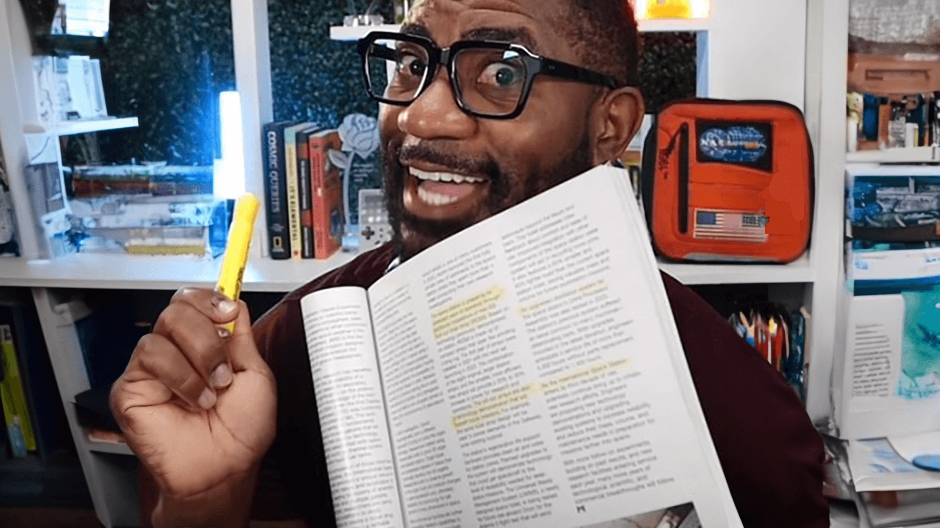 Maynard Okereke holding up a textbook and a highlighter