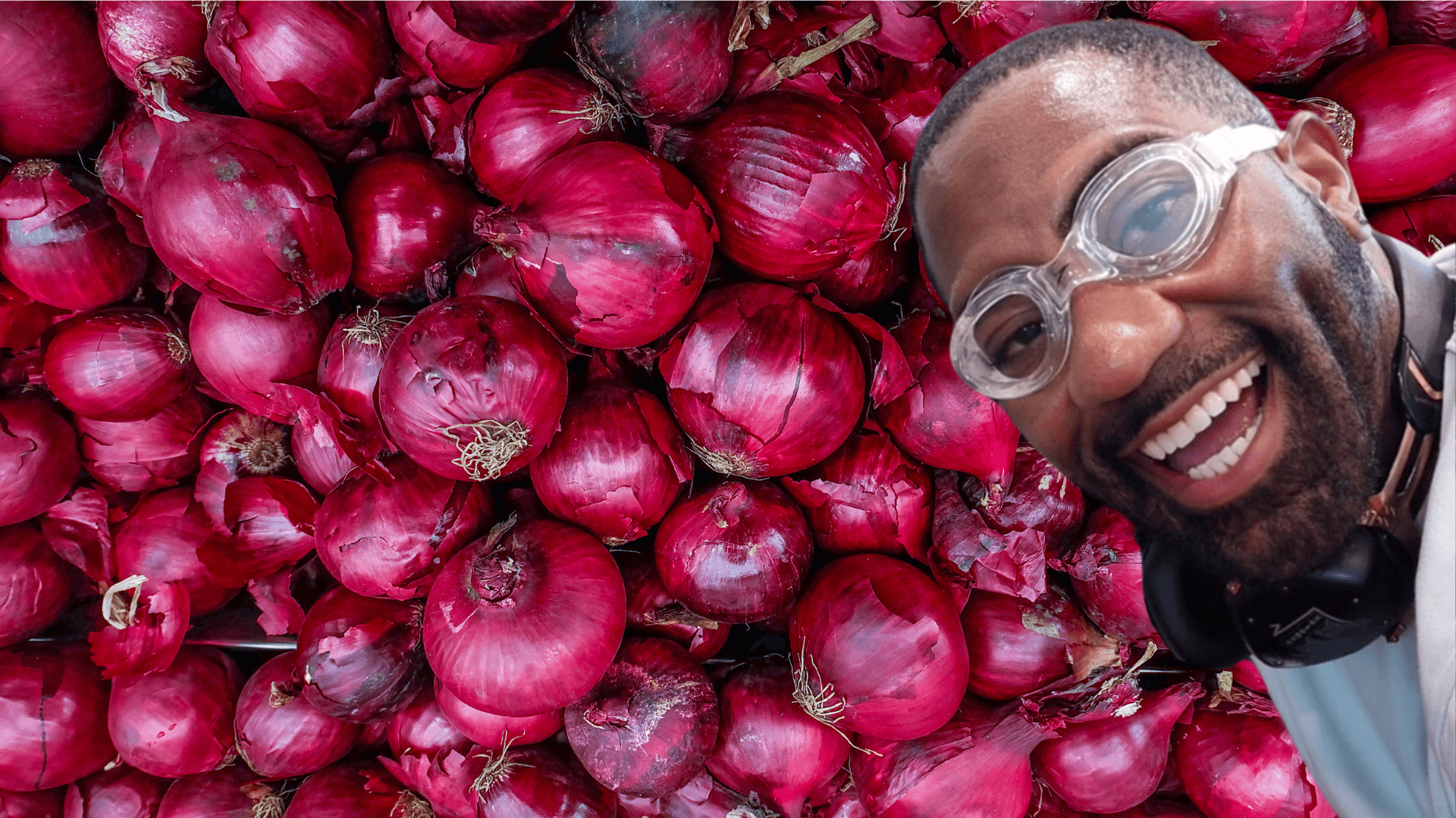 Maynard Okereke wearing googles with onions behind him 