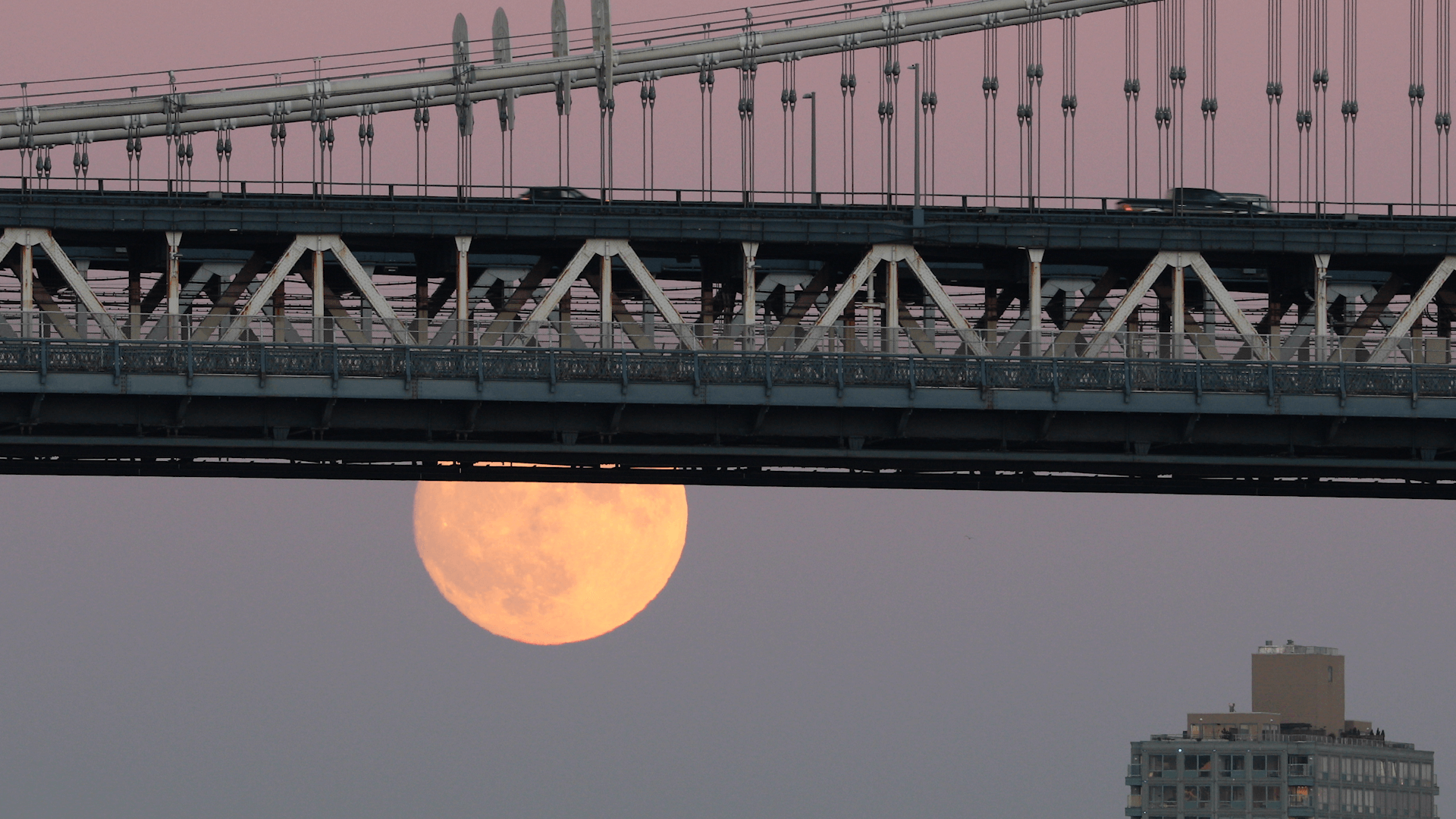 A bright full moon underneath a bridge